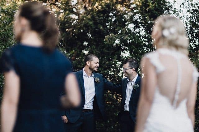 Groomsmen share a moment together with bride and bridesmaids in foreground